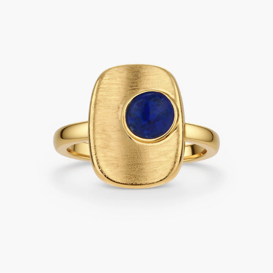 Adjustable gold-plated ring with textured square setting featuring a round blue lapis lazuli stone on cream background.
