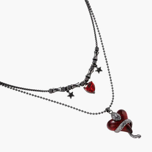 Dark layered necklace set with black chains and red heart pendants, featuring gothic snake design on white background