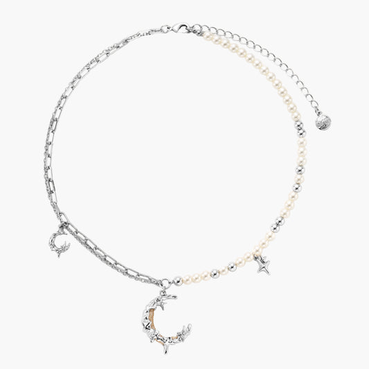 Silver-toned crescent moon pendant with star accents on pearl and chain necklace against white background.