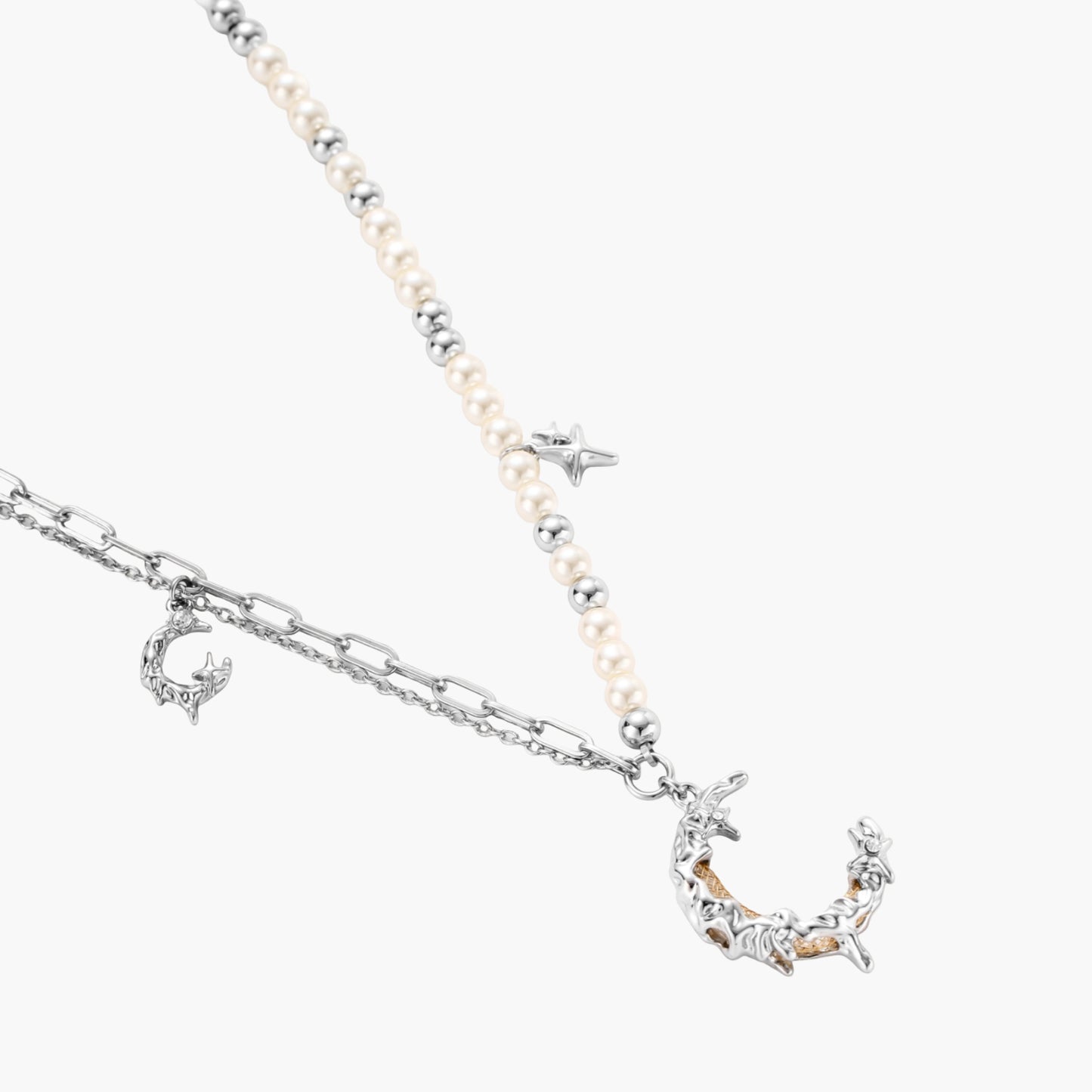 Silver-toned crescent moon pendant with star accents on pearl and chain necklace against white background.