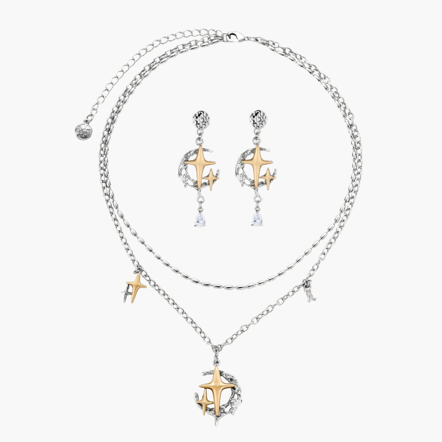 Delicate eco-brass jewelry set featuring gold star and silver moon crescents with clear zirconia crystal drops on cream background