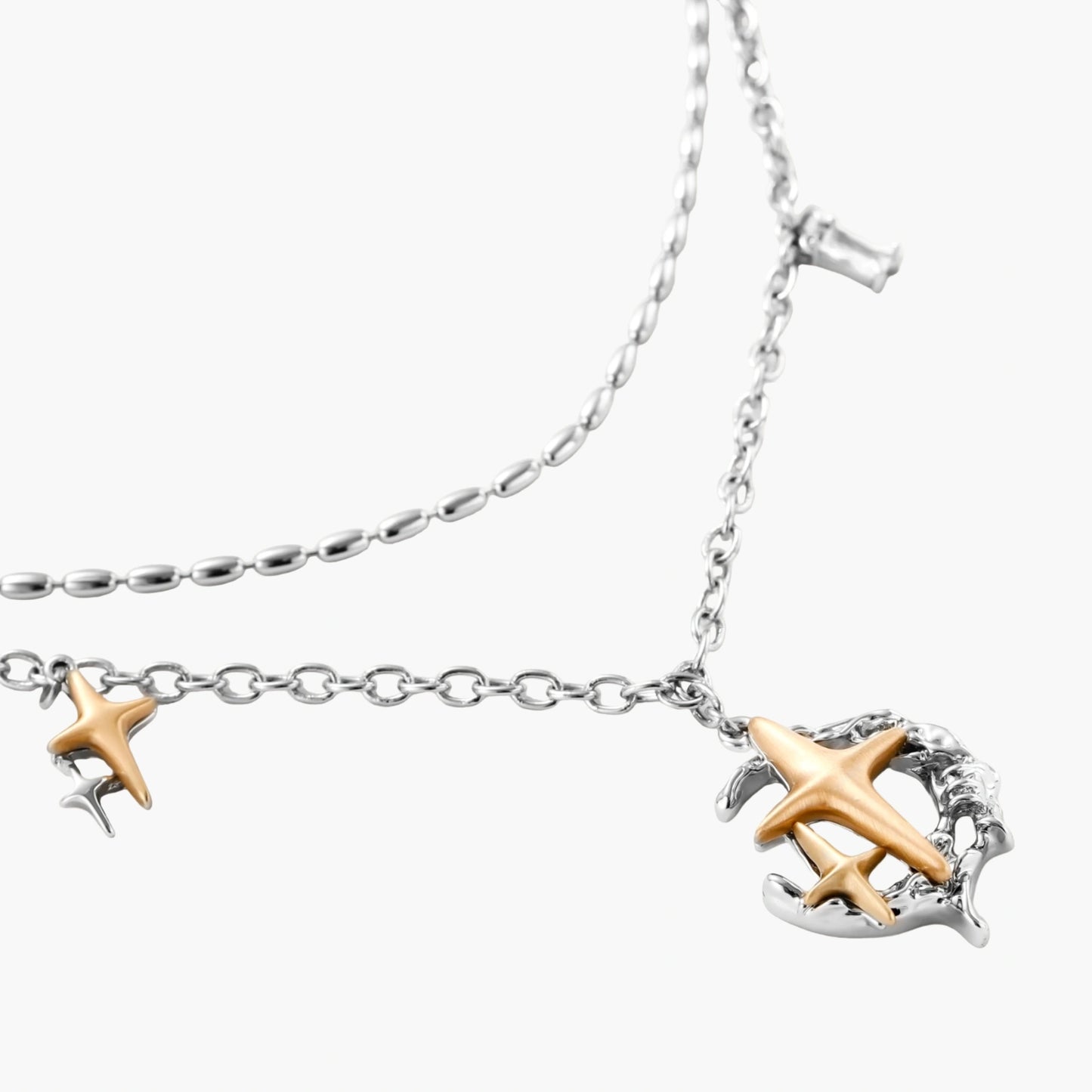 Delicate eco-brass jewelry set featuring gold star and silver moon crescents with clear zirconia crystal drops on cream background