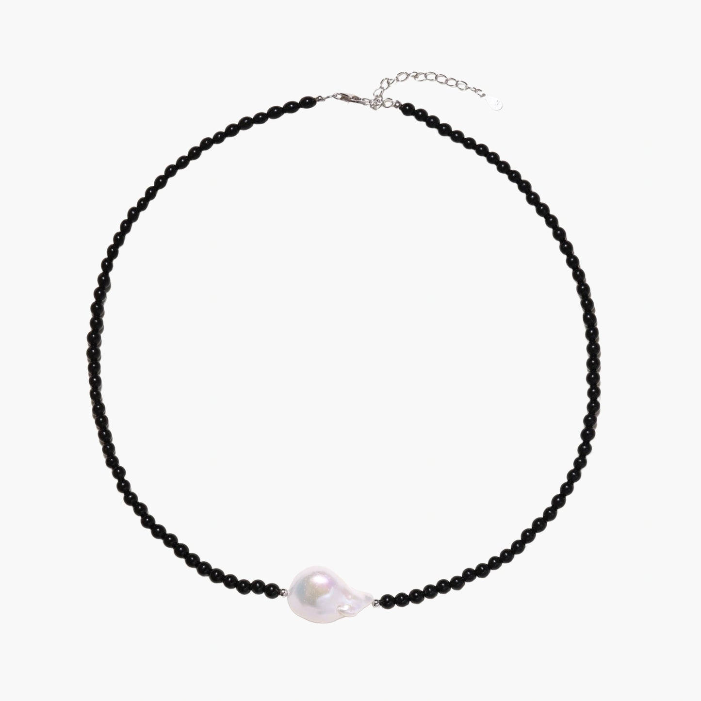Beaded black agate necklace with iridescent baroque freshwater pearl centerpiece on cream background.