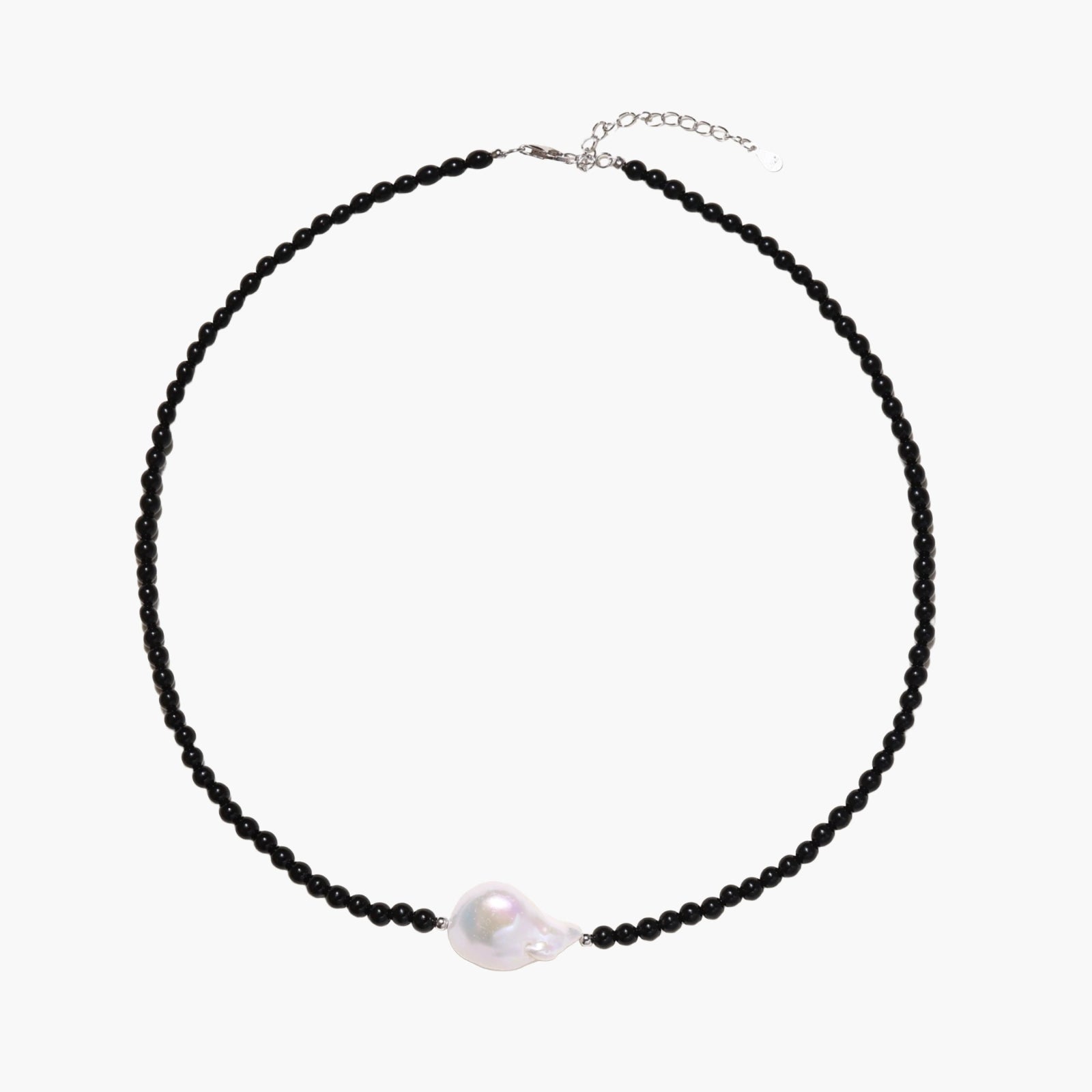 Beaded black agate necklace with iridescent baroque freshwater pearl centerpiece on cream background.