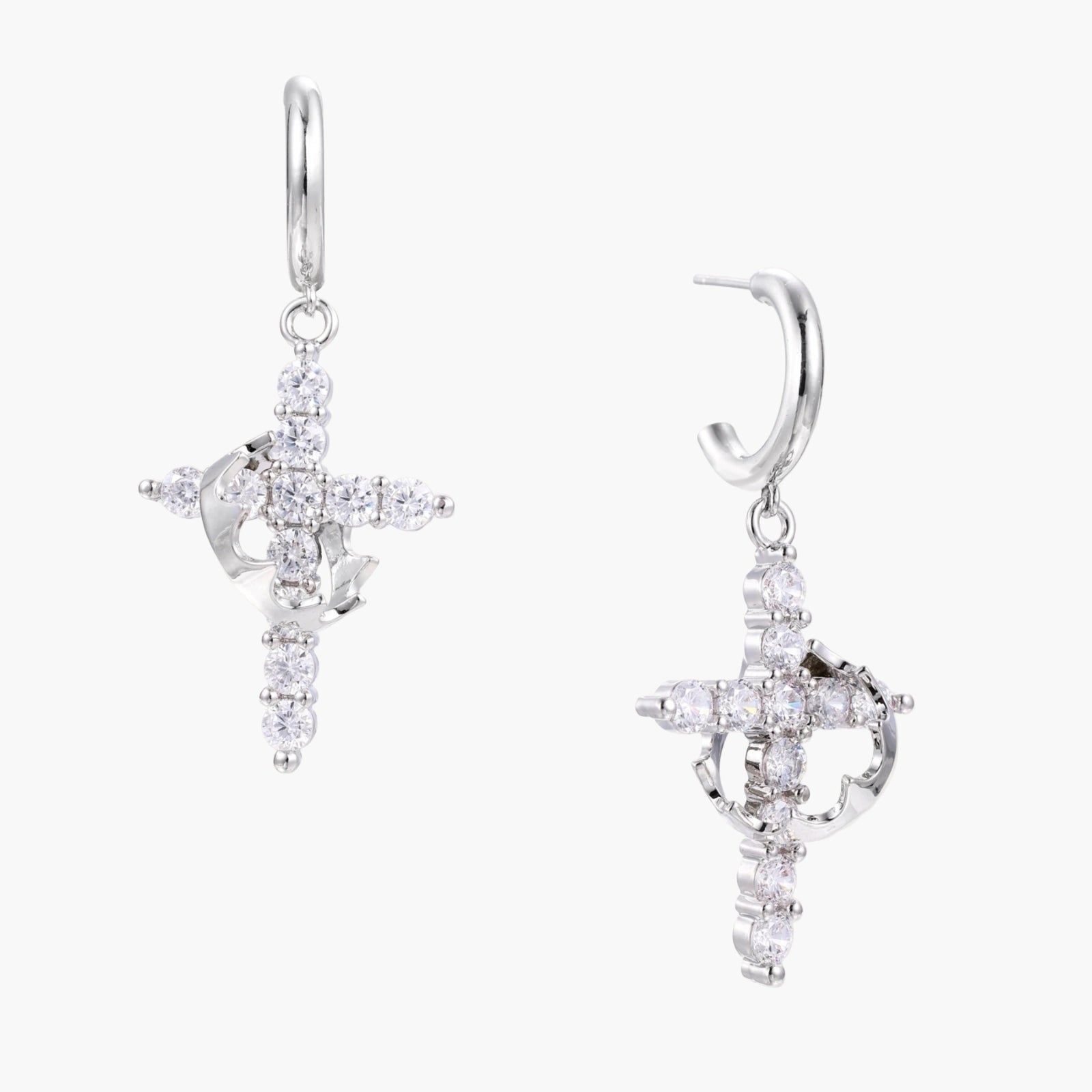 White gold-plated hoop earrings with sparkling zirconia cross charms dangling against cream background