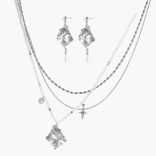 Ornate silver-toned masquerade mask jewelry set featuring rhinestone details and pearl drop earrings on white background.