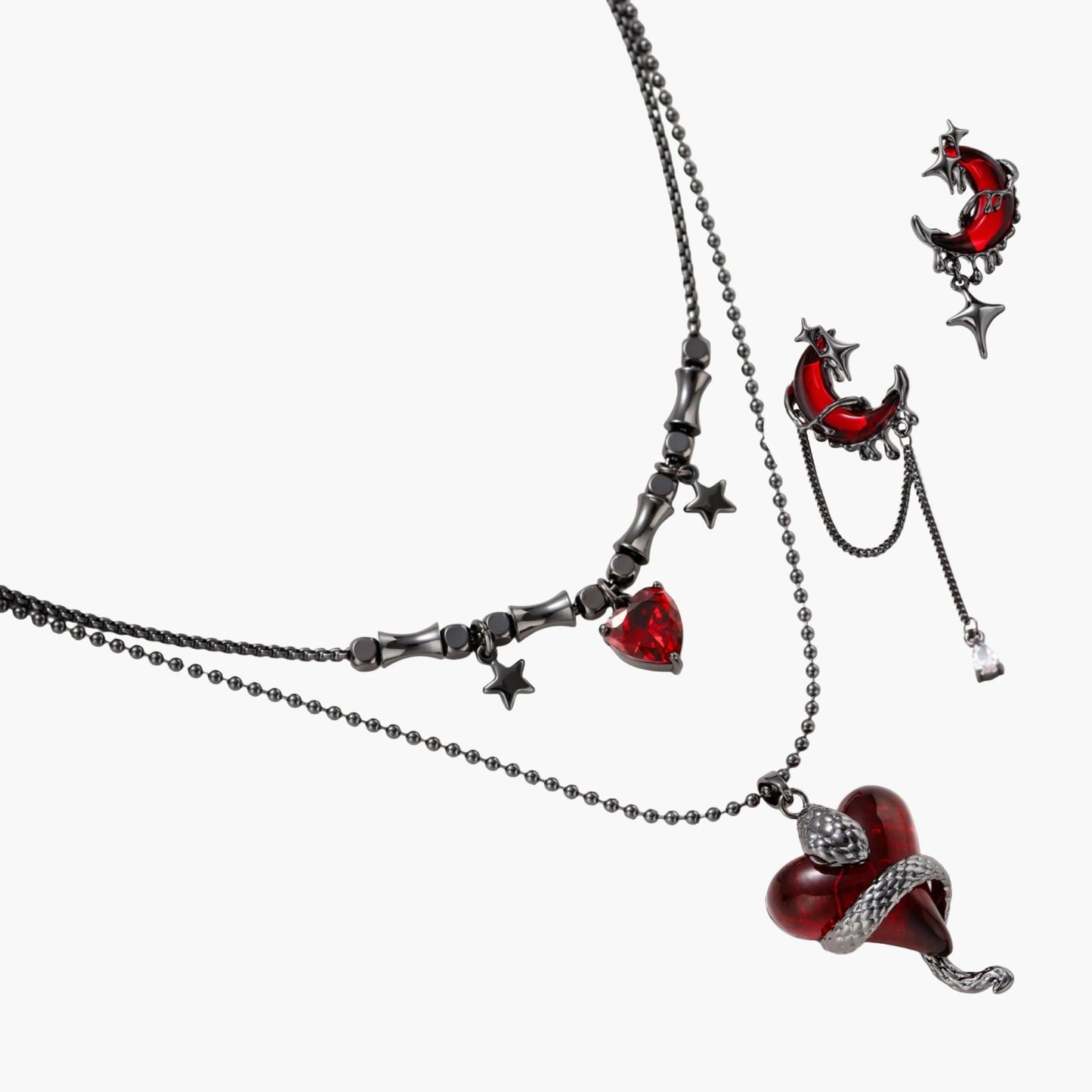 Gothic jewelry set with asymmetrical black metal earrings featuring red crescent moons, stars, and layered necklaces with heart pendants