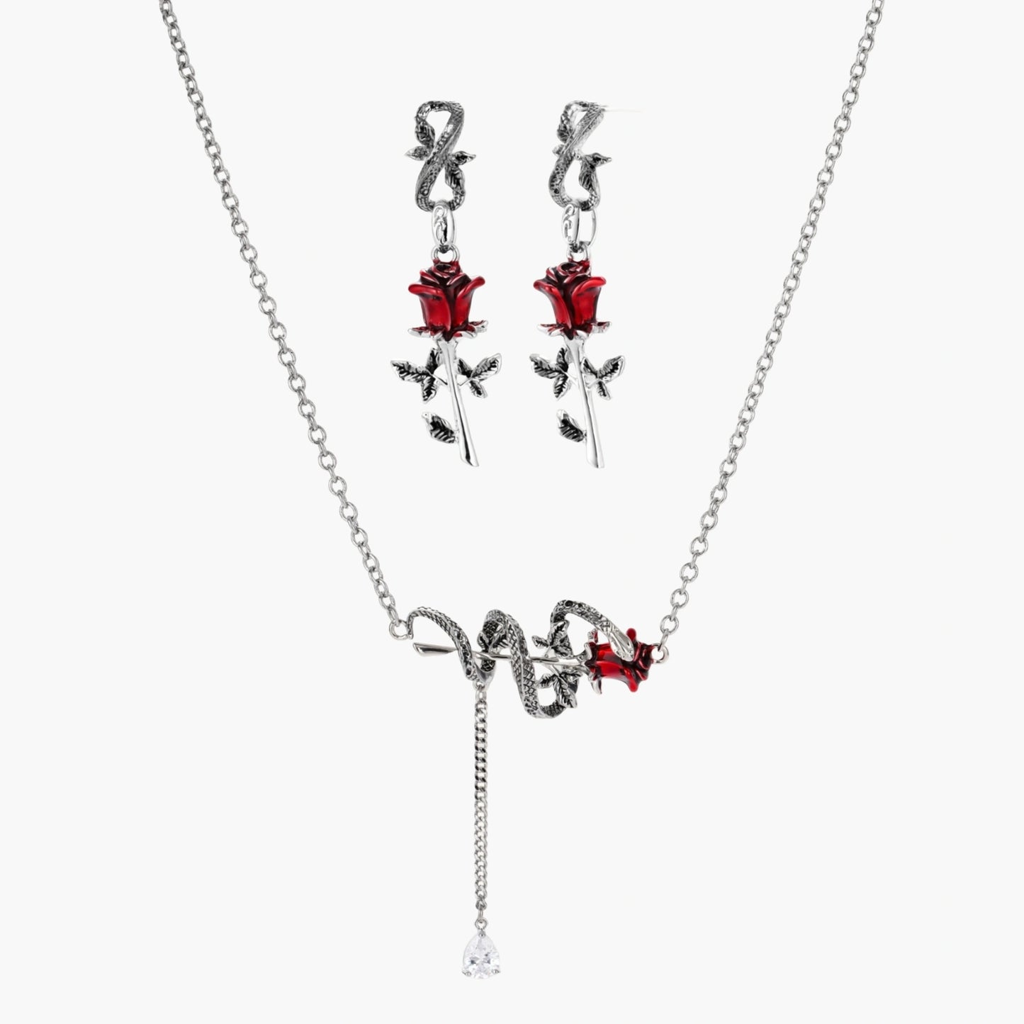 Gothic jewelry set with silver snake designs holding red enamel roses, featuring detailed leaf stems on cream background