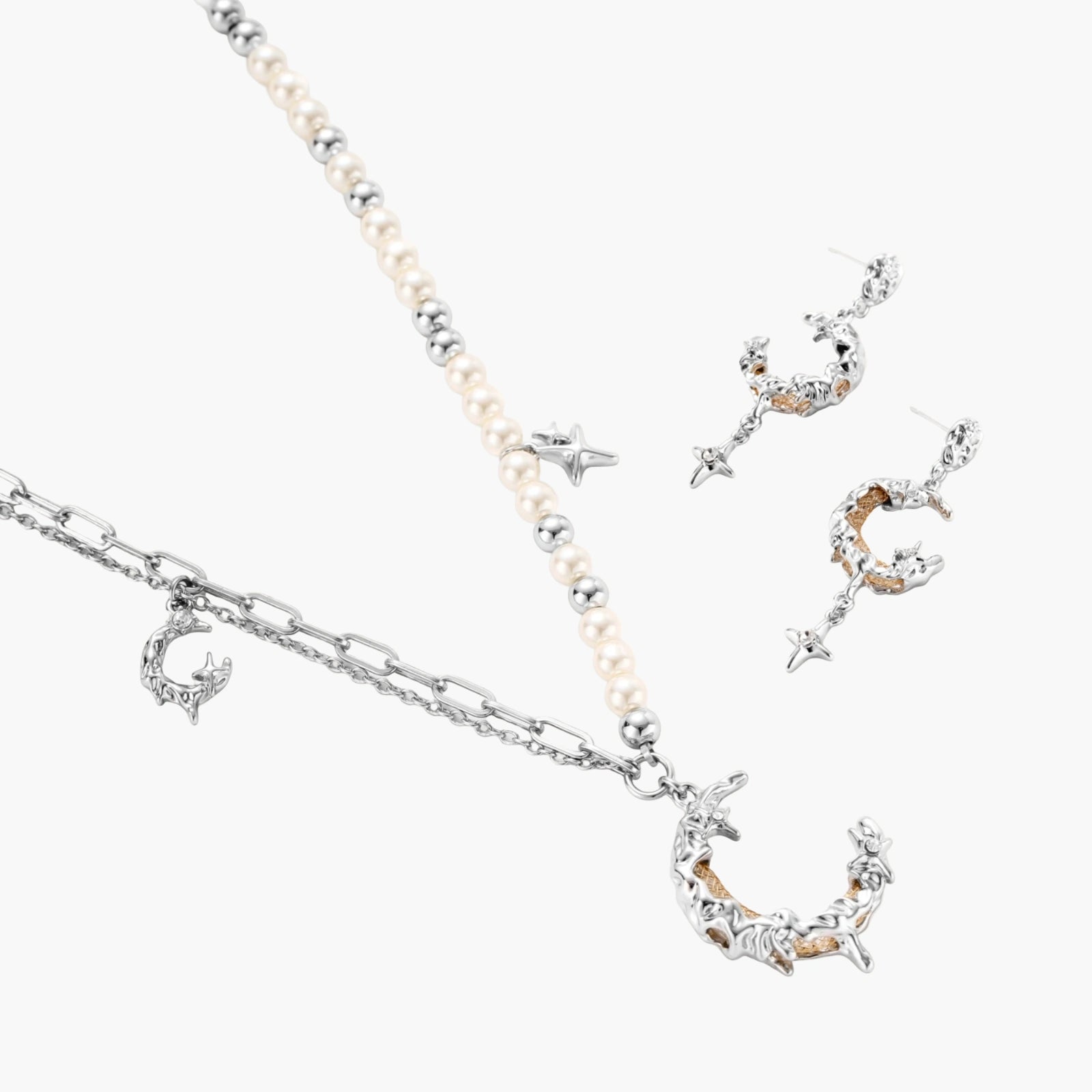 Mixed-metal jewelry set featuring layered necklaces with crescent moon pendant and pearl beads, plus matching star-drop earrings.