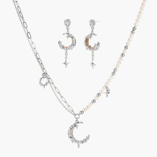 Mixed-metal jewelry set featuring layered necklaces with crescent moon pendant and pearl beads, plus matching star-drop earrings.