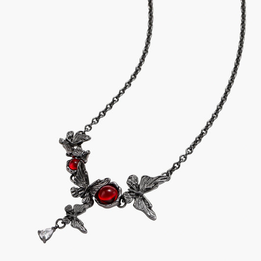 Dark oxidized metal necklace featuring red resin stones set in decorative leaf vine design with crystal drop pendant.