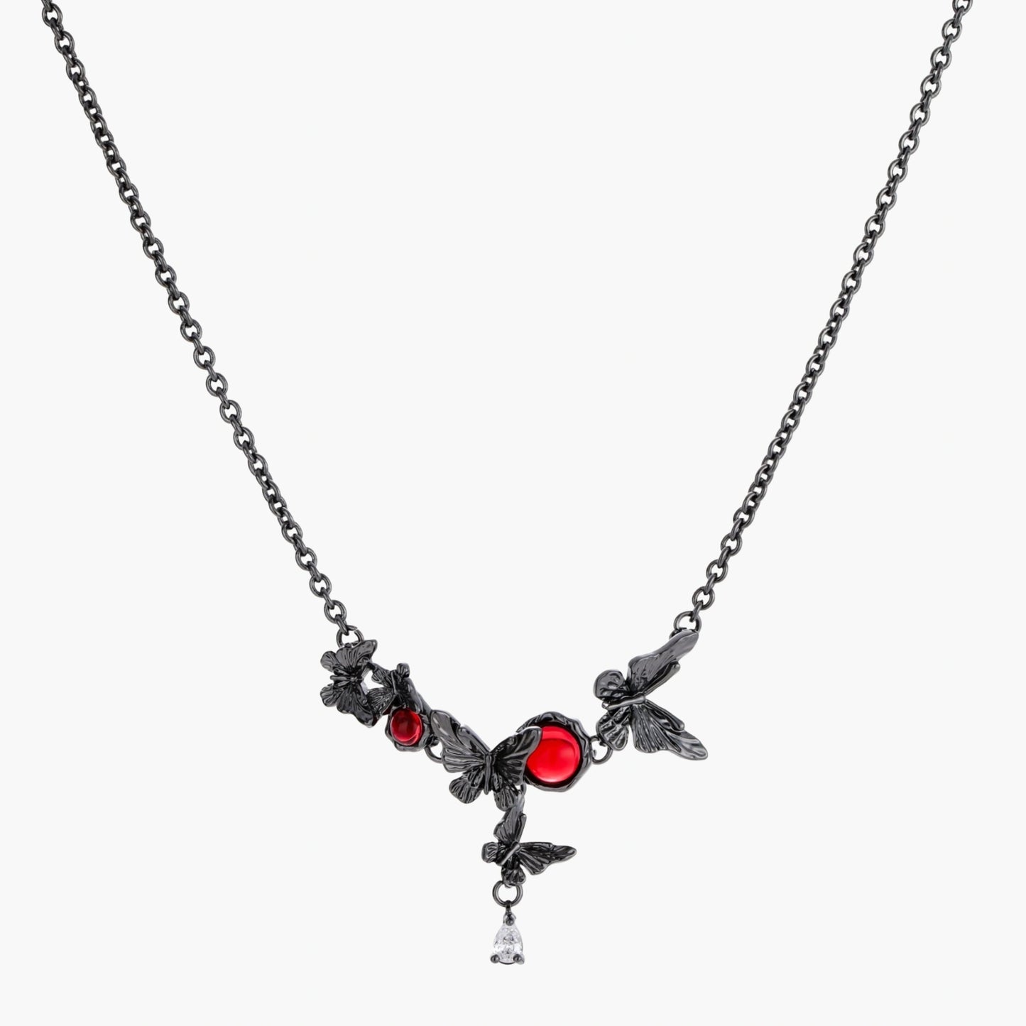 Dark oxidized metal necklace featuring red resin stones set in decorative leaf vine design with crystal drop pendant.