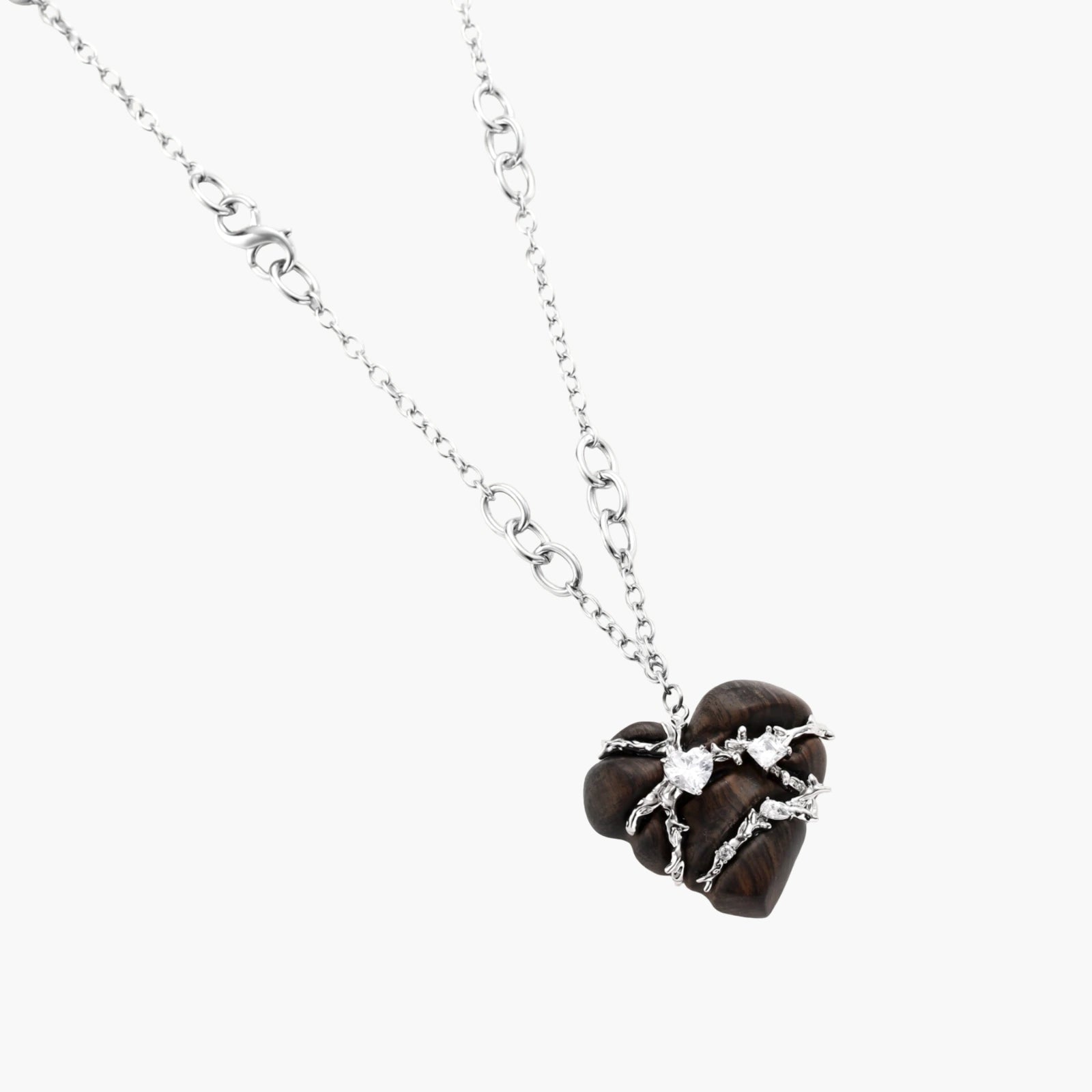 Dark ebony wood heart charms wrapped in intricate silver chains with crystal accents, shown as matching earrings and necklace set.