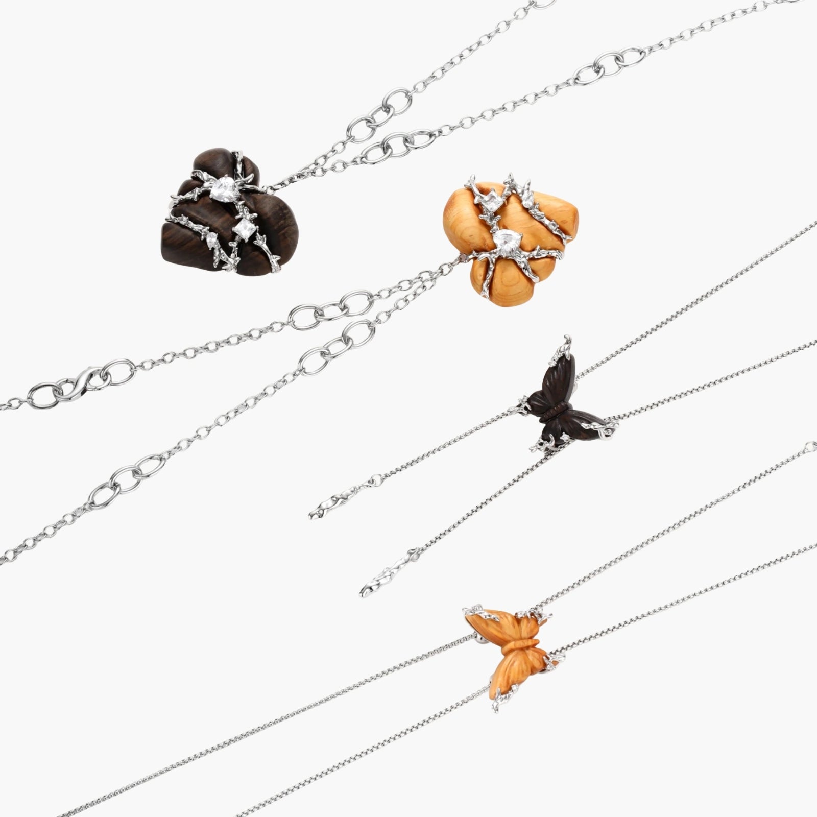 Dark ebony wood heart charms wrapped in intricate silver chains with crystal accents, shown as matching earrings and necklace set.