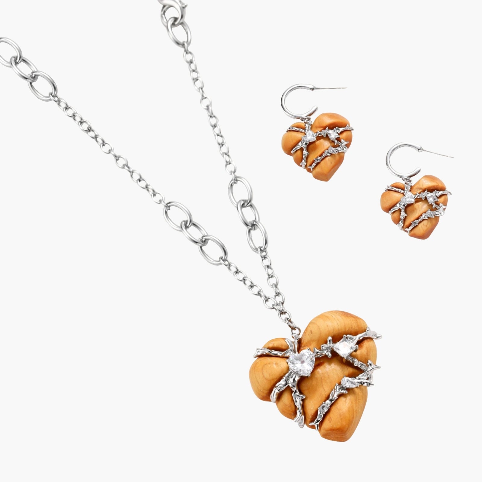 Heart-shaped eco-brass and wood jewelry set with silver wire detailing and crystal accents on cream background.