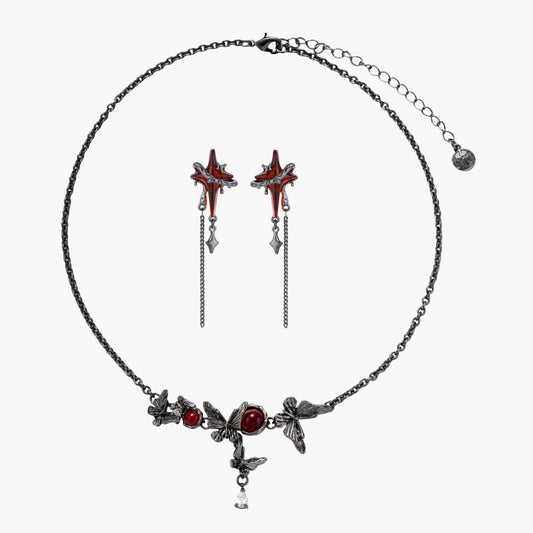 Gothic jewelry set with red resin cross pendants wrapped in dark metal chains on cream background.