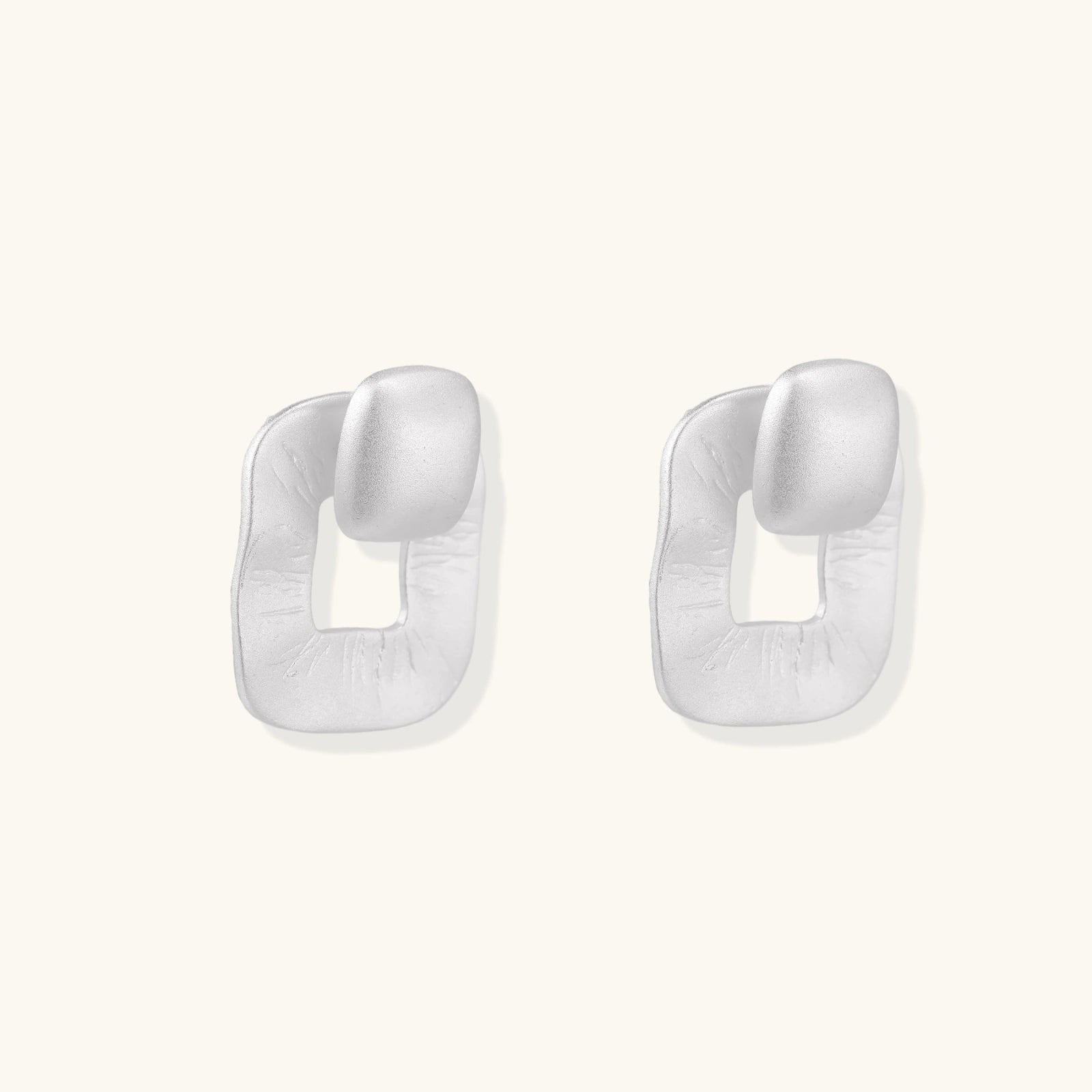 Pair of geometric sterling silver earrings with frosted square frames and glossy rounded studs on white background